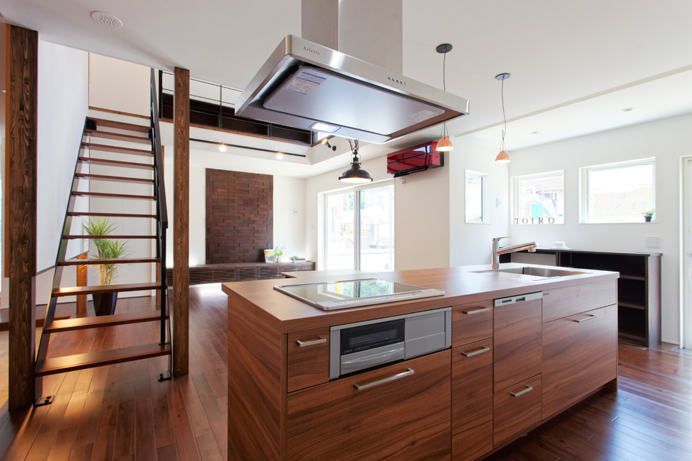 World-inspired single-wall kitchen/diner with a submerged sink, flat-panel cabinets, medium wood cabinets, brown splashback, stainless steel appliances, dark hardwood flooring, an island and brown floors.