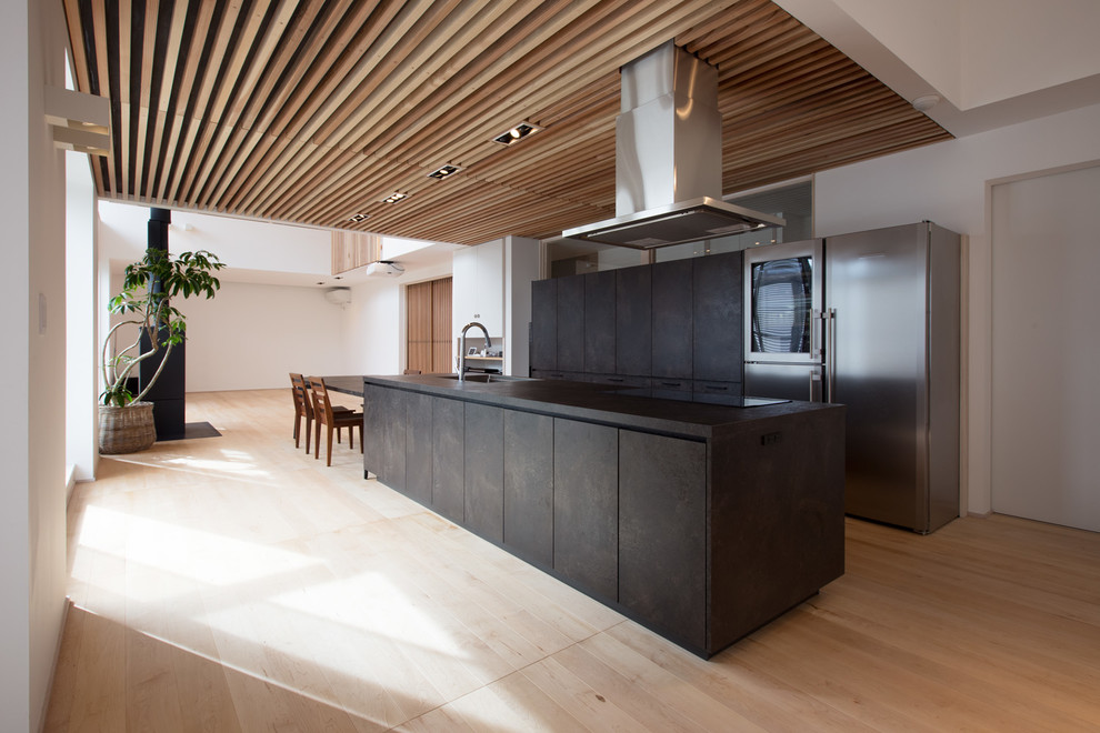 Exempel på ett modernt svart linjärt svart kök med öppen planlösning, med en undermonterad diskho, luckor med profilerade fronter, skåp i slitet trä, rostfria vitvaror, ljust trägolv, en köksö och beiget golv