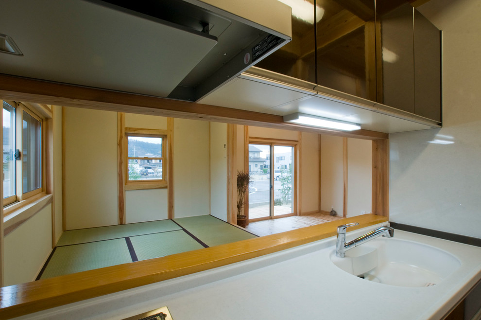 Example of a zen single-wall medium tone wood floor and brown floor enclosed kitchen design in Other with an integrated sink, flat-panel cabinets, brown cabinets, solid surface countertops, brown backsplash, glass tile backsplash, an island and white countertops