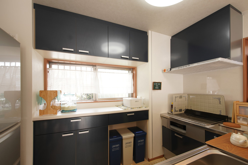 This is an example of a small nautical u-shaped open plan kitchen in Tokyo Suburbs with blue cabinets, stainless steel worktops and white splashback.