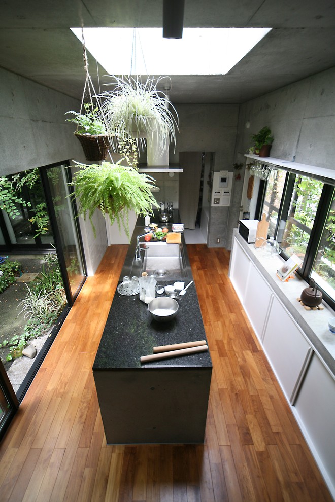 Пример оригинального дизайна: параллельная кухня в стиле лофт с врезной мойкой, плоскими фасадами, техникой из нержавеющей стали, паркетным полом среднего тона и полуостровом