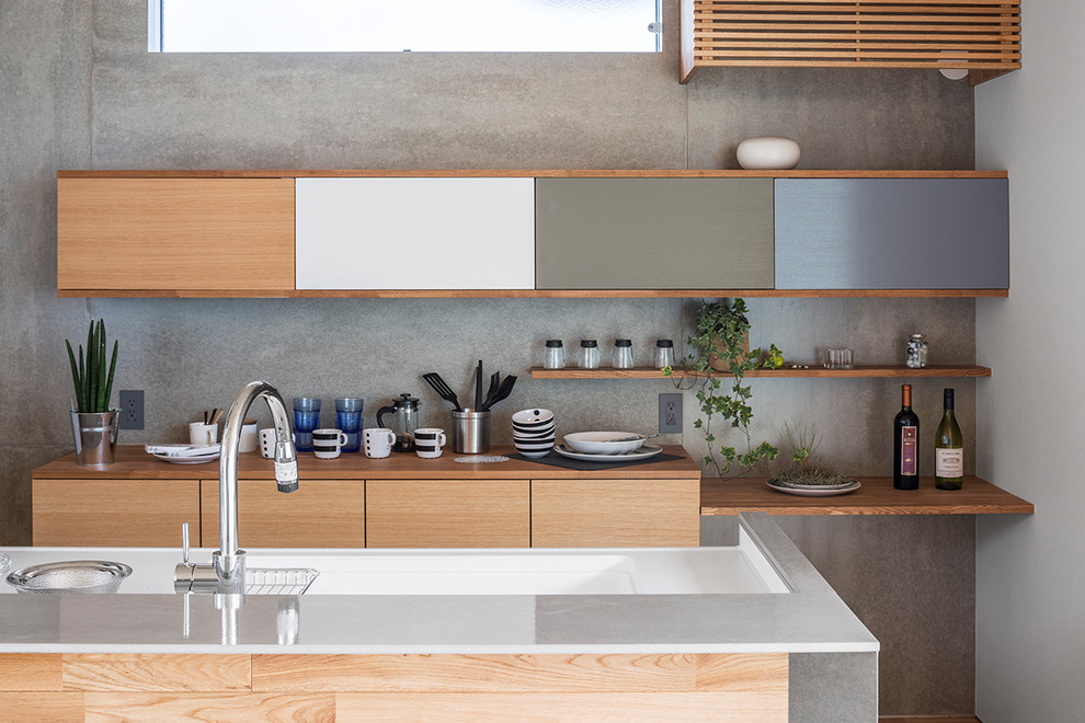 Cette photo montre une cuisine parallèle tendance en bois brun avec un placard à porte plane, une crédence grise, une crédence en dalle de pierre et îlot.