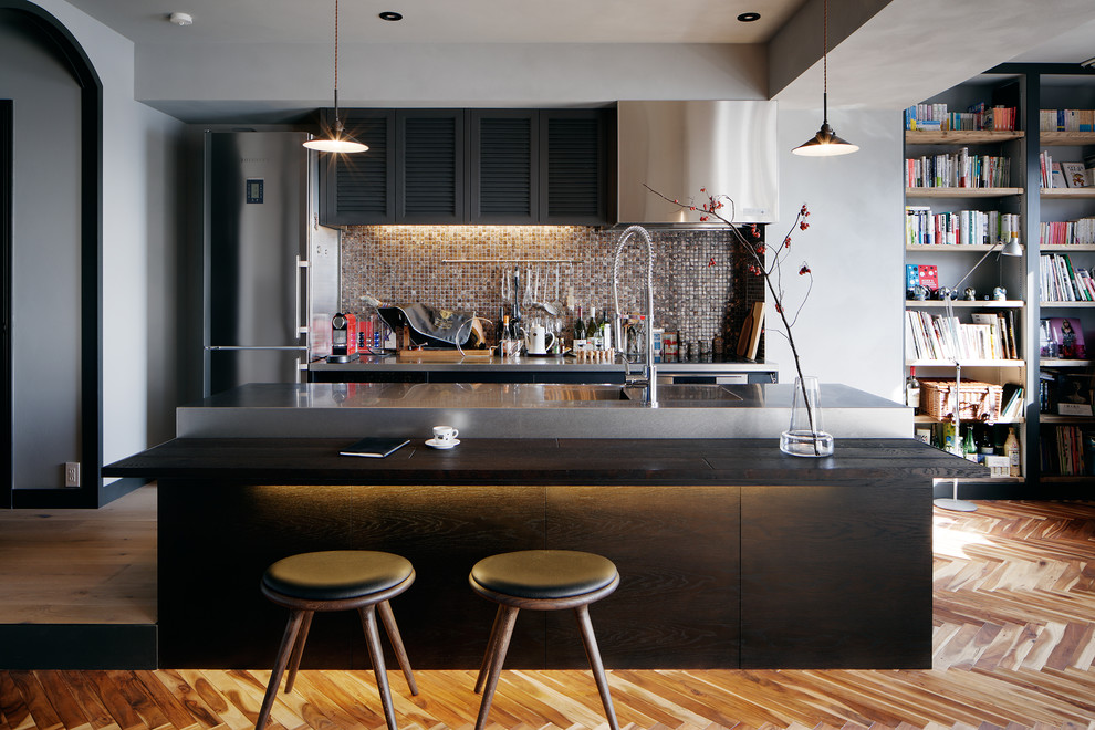 Eklektisk inredning av ett svart linjärt svart kök med öppen planlösning, med en integrerad diskho, släta luckor, mellanmörkt trägolv, en köksö och brunt golv