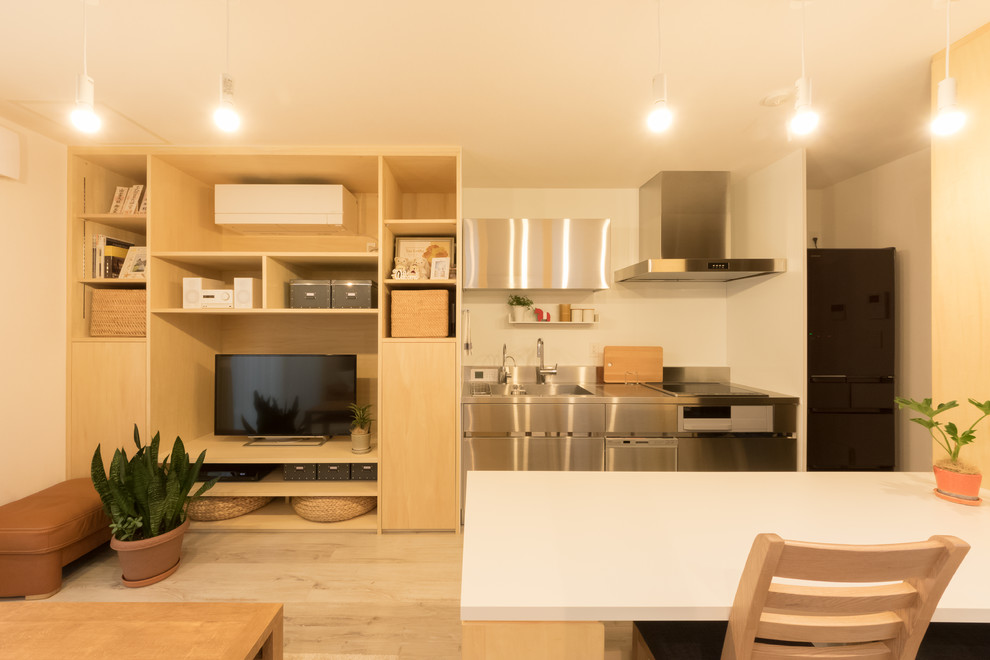 Cette photo montre une petite cuisine ouverte linéaire scandinave en inox avec un évier 1 bac, un placard à porte plane, un plan de travail en inox, parquet peint et un sol marron.