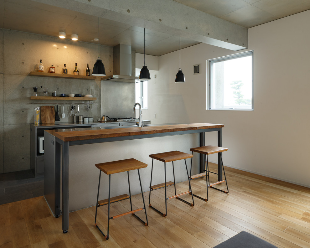Modelo de cocina urbana abierta con puertas de armario grises, encimera de acero inoxidable y suelo gris