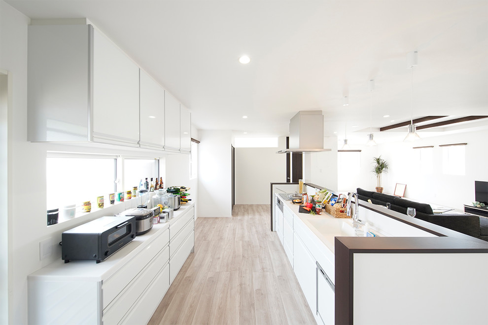 Exemple d'une cuisine ouverte linéaire tendance avec un évier intégré, un placard à porte plane, des portes de placard blanches, îlot, un sol gris et un plan de travail blanc.