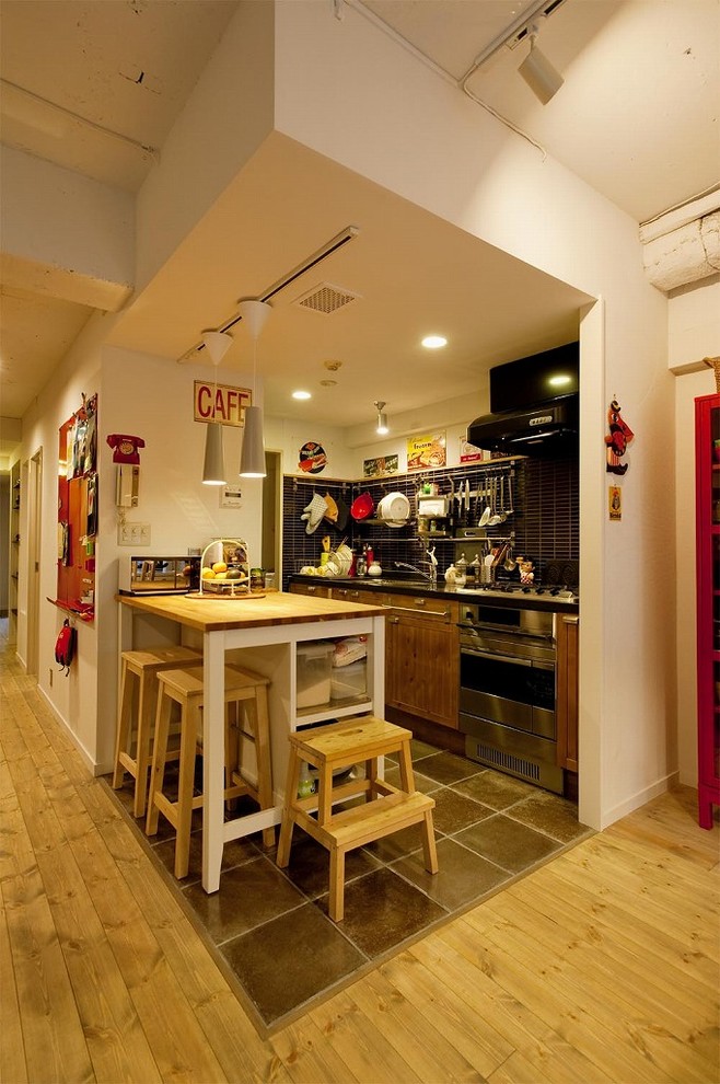 東京23区にあるエクレクティックスタイルのおしゃれなキッチン (シングルシンク、フラットパネル扉のキャビネット、中間色木目調キャビネット、ステンレスカウンター、青いキッチンパネル、茶色い床、茶色いキッチンカウンター) の写真
