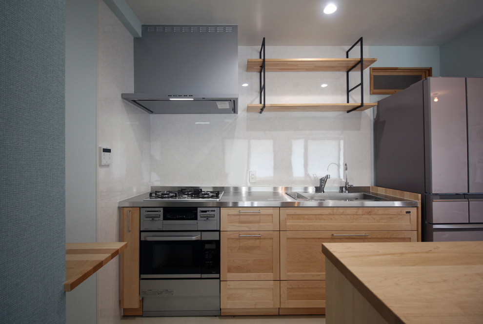 神戸にある北欧スタイルのおしゃれなキッチン (一体型シンク、淡色木目調キャビネット、ステンレスカウンター、白いキッチンパネル、ガラス板のキッチンパネル、カラー調理設備、無垢フローリング、茶色い床) の写真