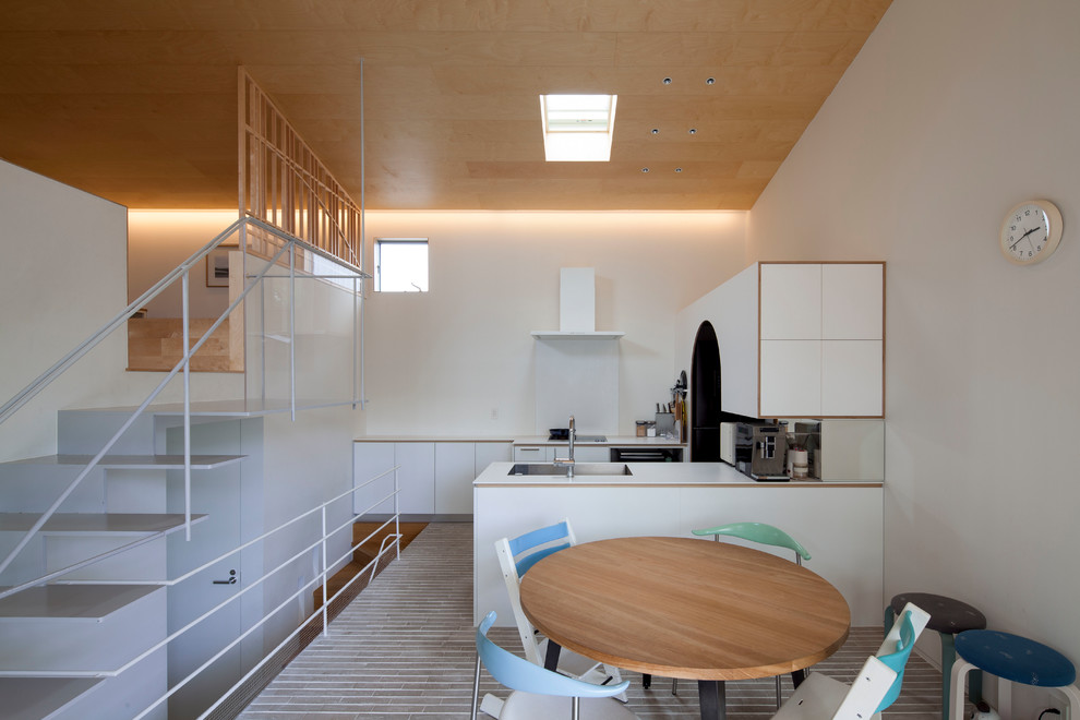 横浜にあるアジアンスタイルのおしゃれなキッチン (アンダーカウンターシンク、フラットパネル扉のキャビネット、白いキャビネット、白いキッチンパネル、シルバーの調理設備、黒い床、白いキッチンカウンター) の写真