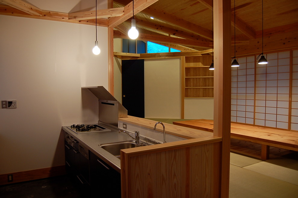 Offene, Einzeilige Asiatische Küche mit integriertem Waschbecken, Edelstahl-Arbeitsplatte, Küchenrückwand in Schwarz, Glasrückwand, Betonboden und Kücheninsel in Fukuoka