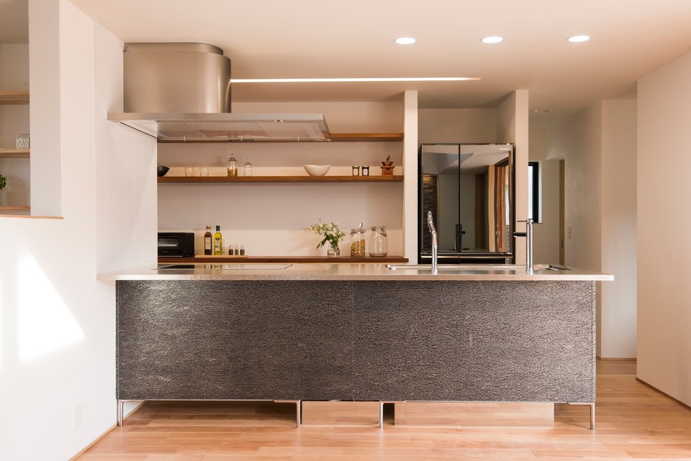 Esempio di una cucina minimal con top in acciaio inossidabile, paraspruzzi grigio, pavimento in legno massello medio e pavimento marrone