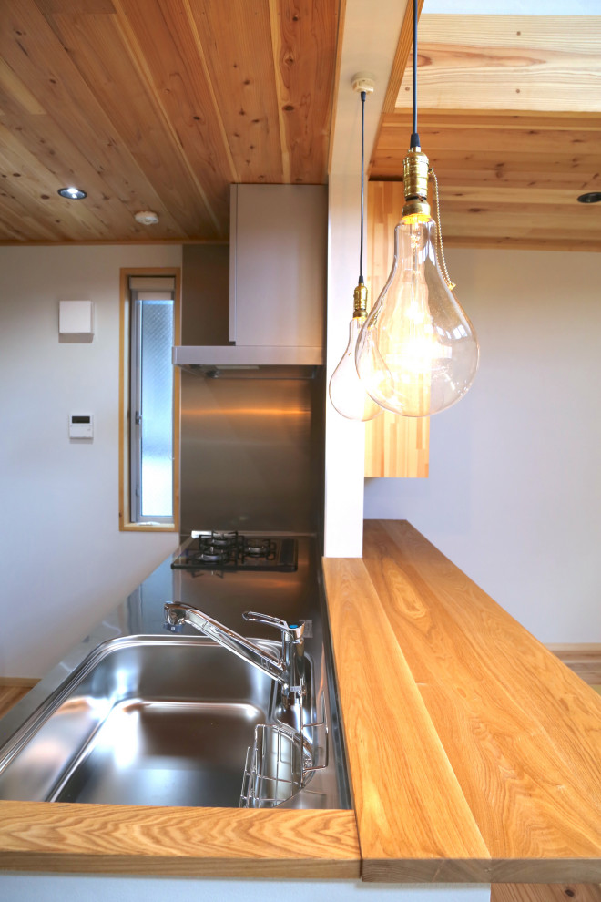 Immagine di una cucina chic di medie dimensioni con ante in acciaio inossidabile, top in acciaio inossidabile, paraspruzzi bianco, pavimento in legno massello medio, pavimento beige e top beige