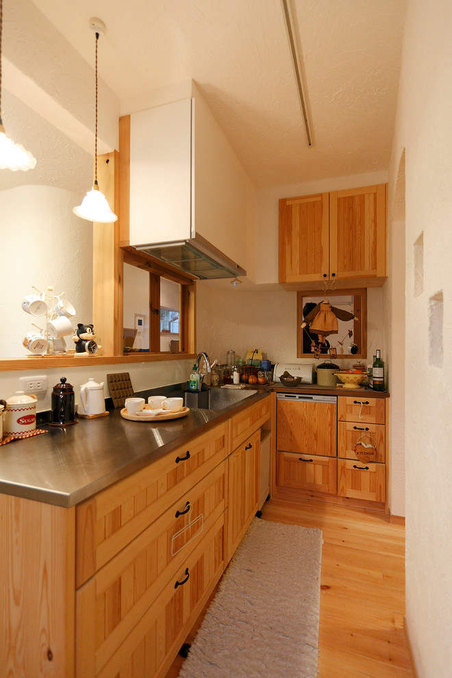 大阪にあるカントリー風のおしゃれなキッチン (一体型シンク、落し込みパネル扉のキャビネット、中間色木目調キャビネット、ステンレスカウンター、無垢フローリング、茶色い床、茶色いキッチンカウンター) の写真