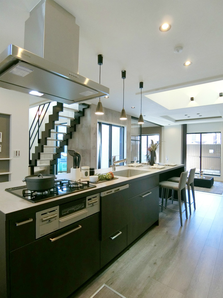 Immagine di una cucina moderna con lavello sottopiano, ante a filo, ante nere, paraspruzzi nero, elettrodomestici in acciaio inossidabile, pavimento beige e top beige