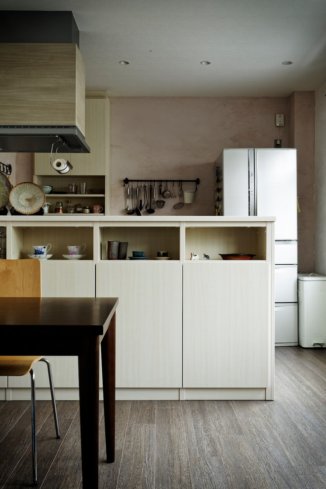 Стильный дизайн: параллельная кухня в стиле лофт с светлыми деревянными фасадами, розовым фартуком, темным паркетным полом и полуостровом - последний тренд