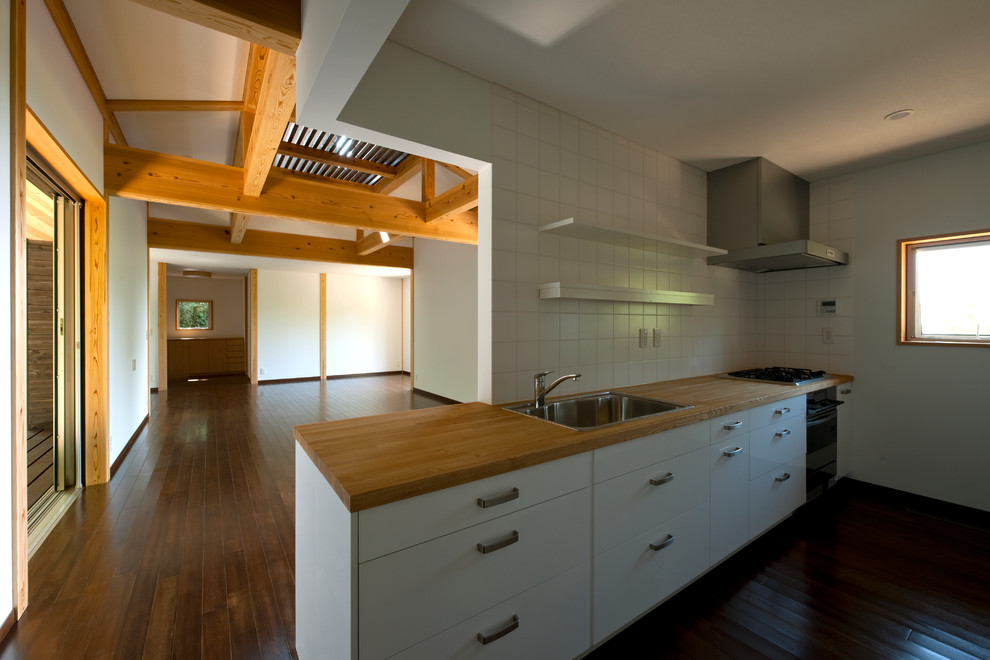 Esempio di una cucina lineare scandinava chiusa e di medie dimensioni con ante bianche, top in legno, paraspruzzi bianco, paraspruzzi in gres porcellanato, 2 o più isole e top marrone