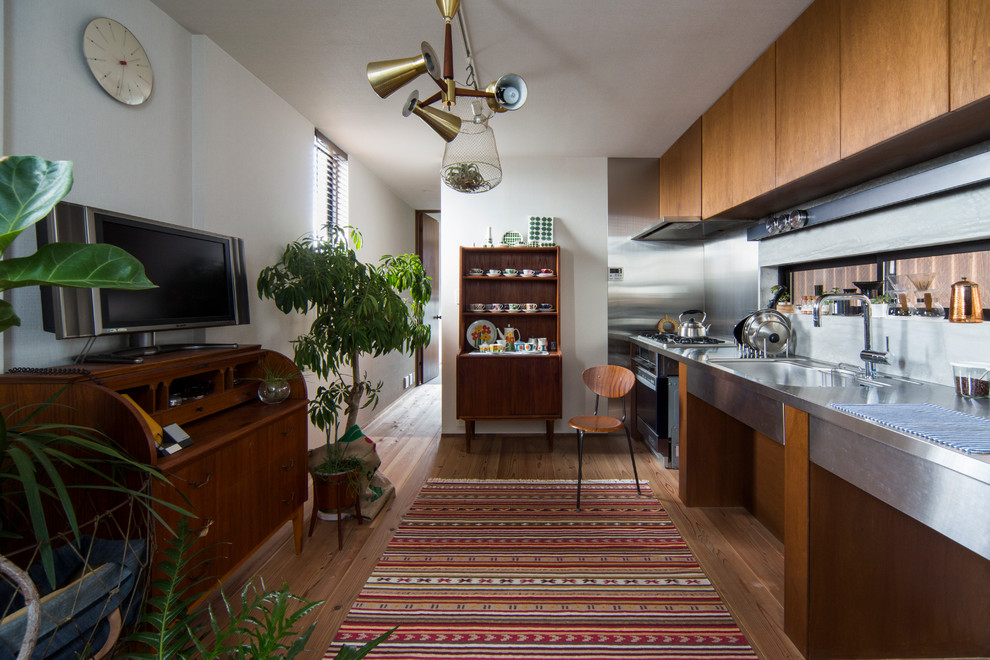 Foto di una cucina lineare design con top in acciaio inossidabile, paraspruzzi a effetto metallico, elettrodomestici in acciaio inossidabile e pavimento in legno massello medio