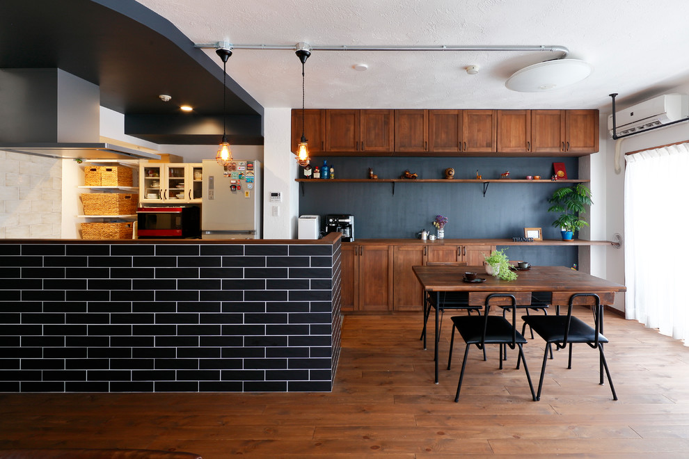 他の地域にあるアジアンスタイルのおしゃれなキッチン (シェーカースタイル扉のキャビネット、中間色木目調キャビネット、木材カウンター、黒いキッチンパネル、無垢フローリング、茶色い床、茶色いキッチンカウンター) の写真