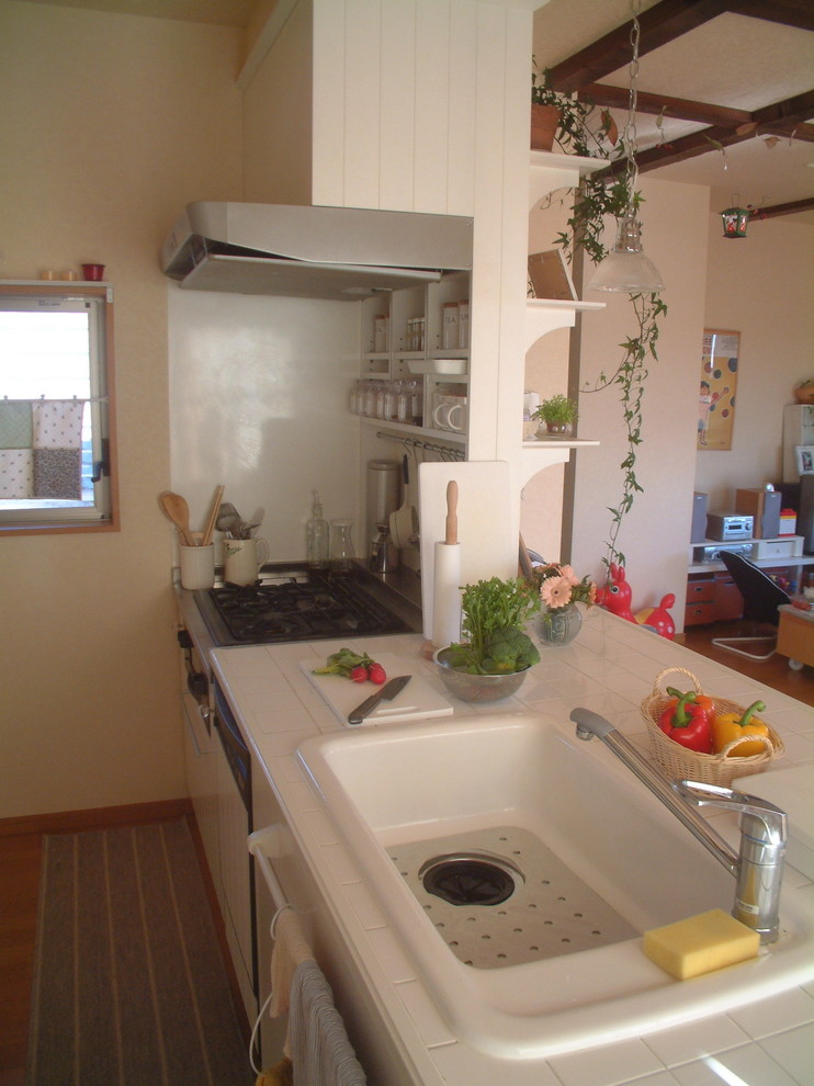На фото: маленькая кухня-гостиная в стиле шебби-шик с одинарной мойкой, столешницей из плитки, белым фартуком, полом из фанеры и полуостровом для на участке и в саду