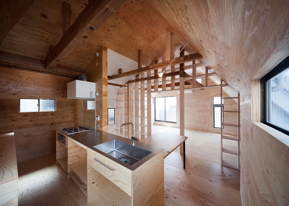 Imagen de cocina lineal urbana abierta con armarios con rebordes decorativos, encimera de acero inoxidable y una isla