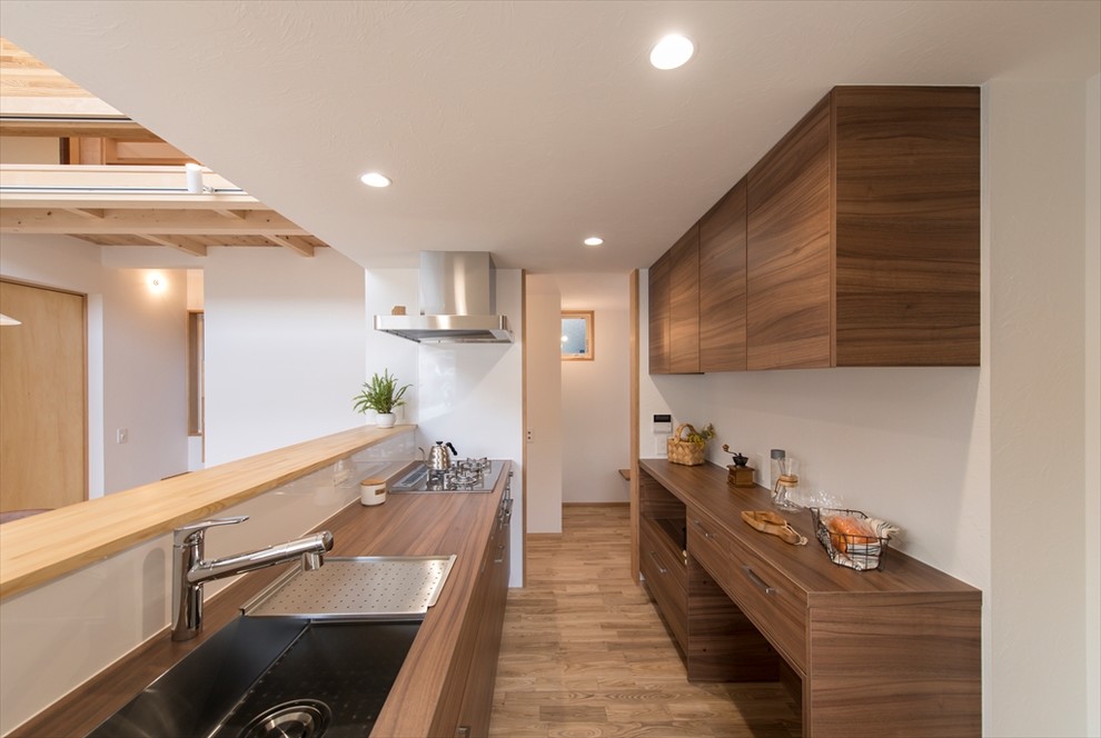 横浜にあるコンテンポラリースタイルのおしゃれなキッチン (シングルシンク、フラットパネル扉のキャビネット、濃色木目調キャビネット、木材カウンター、無垢フローリング、茶色い床、茶色いキッチンカウンター) の写真