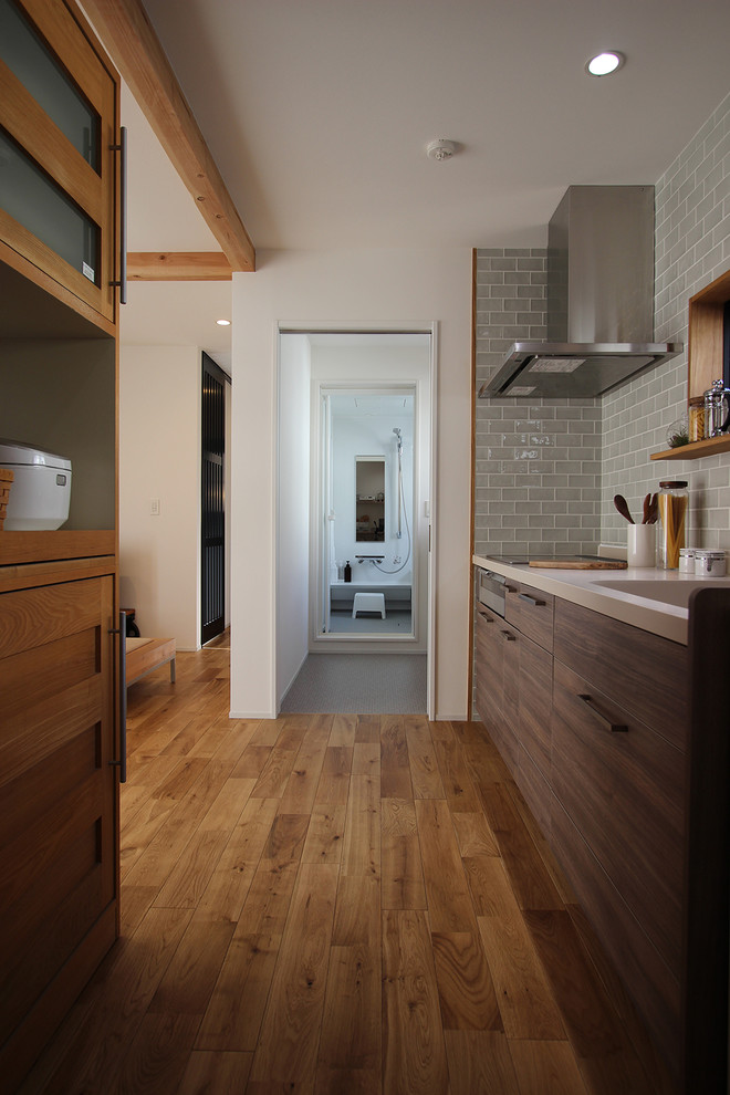 Immagine di una cucina nordica con lavello integrato, ante lisce, ante in legno bruno, paraspruzzi blu, pavimento in legno massello medio e pavimento marrone