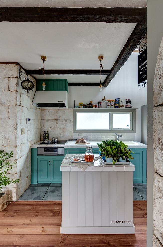 Идея дизайна: прямая кухня-гостиная в стиле шебби-шик с монолитной мойкой, фасадами с утопленной филенкой, зелеными фасадами, островом, серым полом и белой столешницей