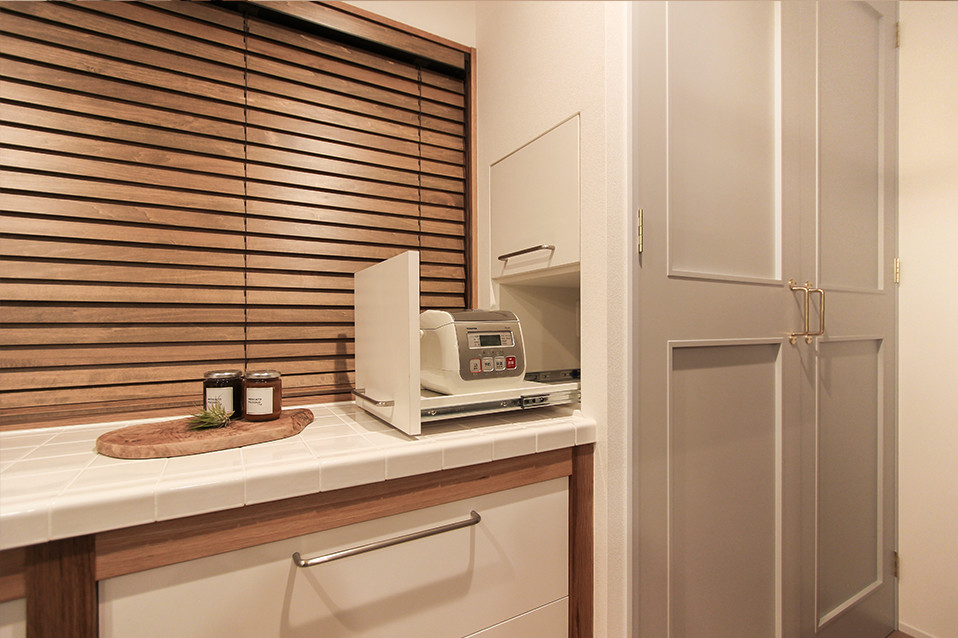 Aménagement d'une petite cuisine scandinave avec un placard à porte affleurante, des portes de placard blanches, plan de travail carrelé et un sol en bois brun.