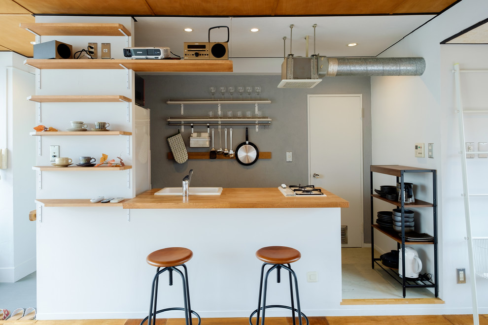 Example of a trendy kitchen design in Tokyo with a drop-in sink, wood countertops and a peninsula
