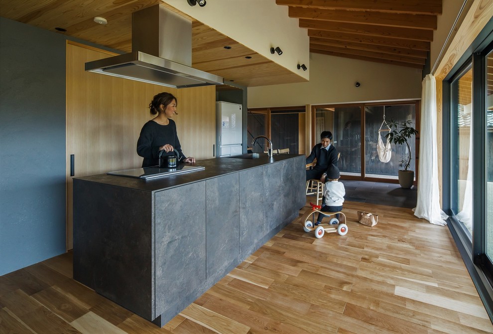 Esempio di una cucina etnica di medie dimensioni con pavimento in legno massello medio, pavimento beige, ante a filo, ante con finitura invecchiata, top alla veneziana, paraspruzzi bianco, paraspruzzi con piastrelle di cemento e top nero