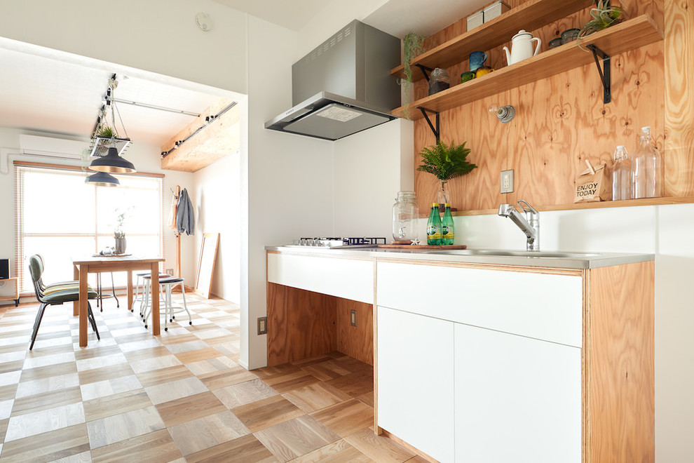 Ejemplo de cocina lineal rústica abierta con puertas de armario blancas, encimera de acero inoxidable, suelo de madera en tonos medios y suelo beige