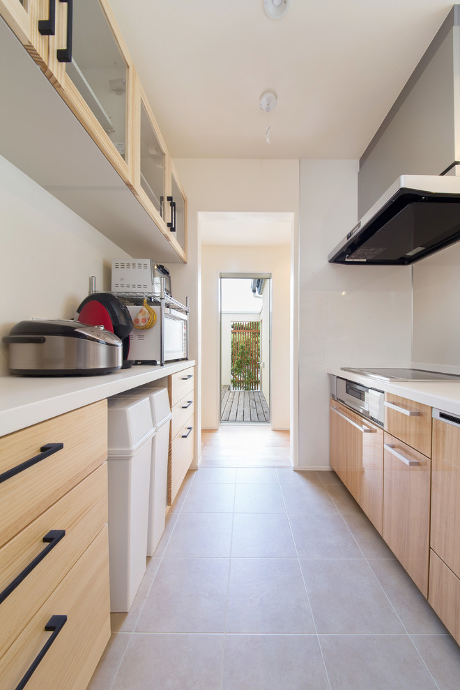 Foto på ett avskilt minimalistiskt linjärt kök, med släta luckor, skåp i ljust trä, en halv köksö och grått golv