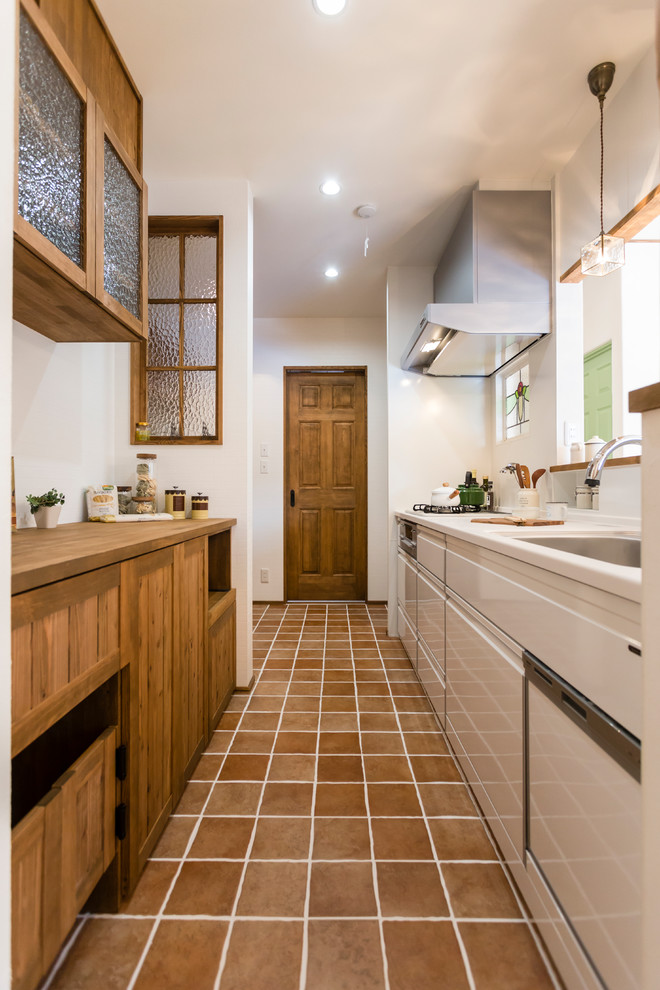 Inspiration för ett medelhavsstil kök, med en enkel diskho, luckor med infälld panel, skåp i mellenmörkt trä, vitt stänkskydd, klinkergolv i terrakotta och brunt golv
