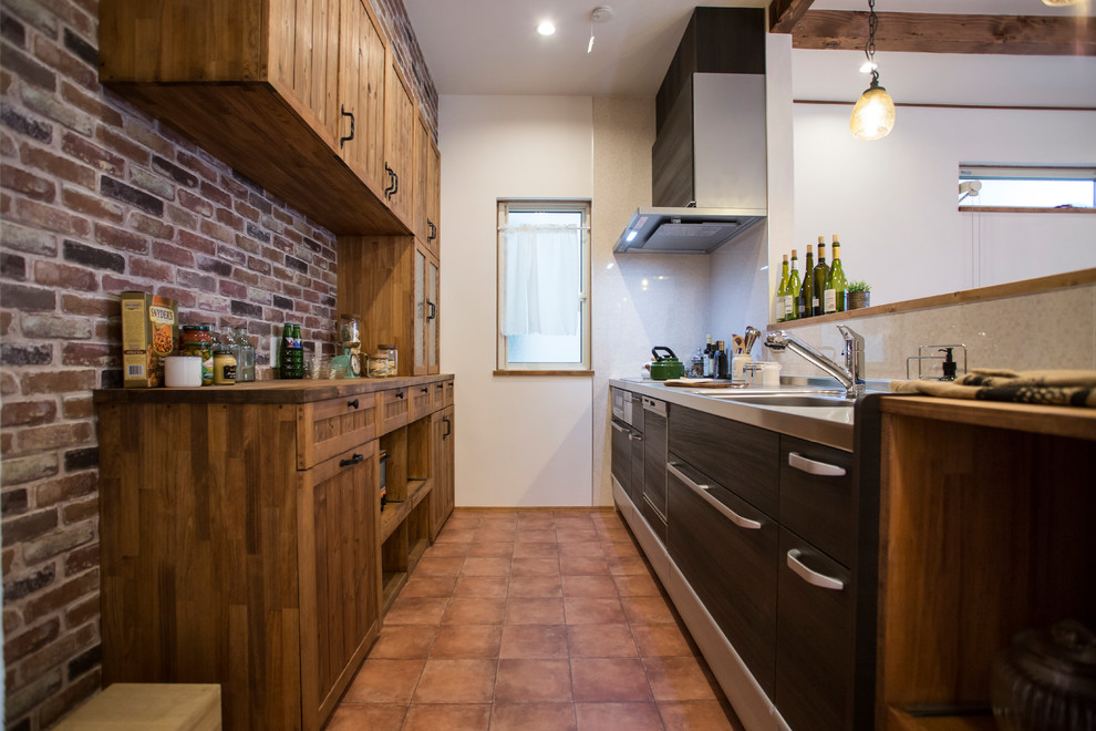 Foto di una cucina parallela mediterranea con lavello a vasca singola, top in acciaio inossidabile, pavimento in terracotta e pavimento arancione