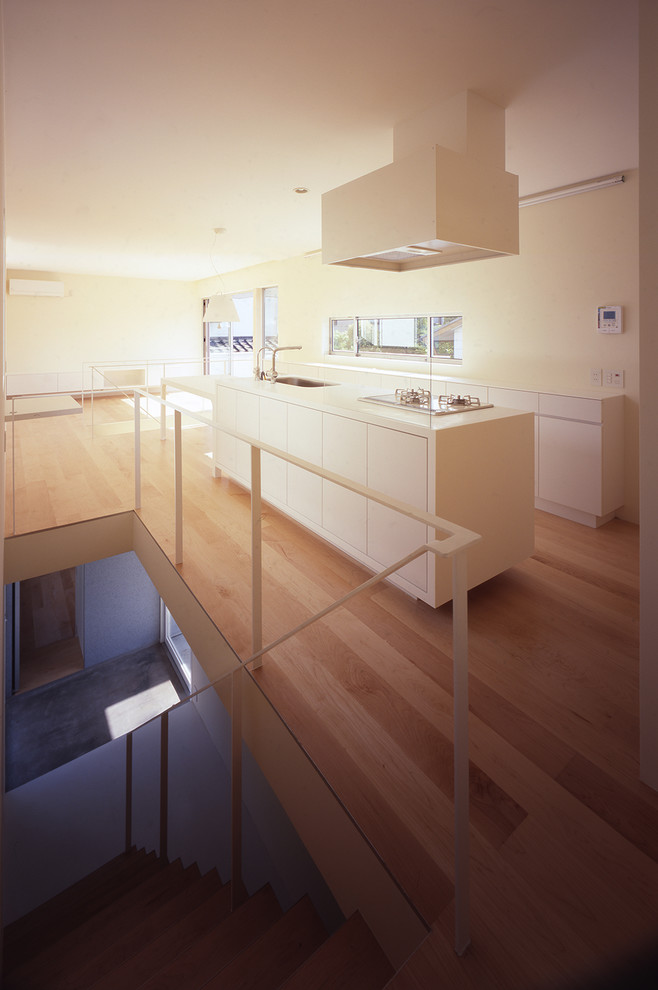 Modelo de cocina moderna abierta con armarios con rebordes decorativos, puertas de armario blancas, encimera de acrílico, una isla y encimeras blancas