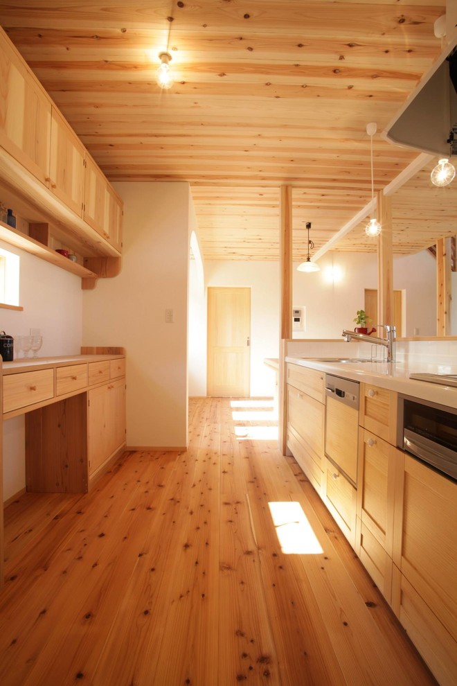 Réalisation d'une cuisine linéaire champêtre en bois clair avec un placard à porte shaker, une crédence blanche et un sol en bois brun.