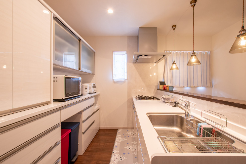 Photo of a scandi single-wall open plan kitchen in Other with a submerged sink, flat-panel cabinets, white cabinets, marble worktops, white splashback, white appliances, plywood flooring, a breakfast bar, brown floors, white worktops and glass sheet splashback.