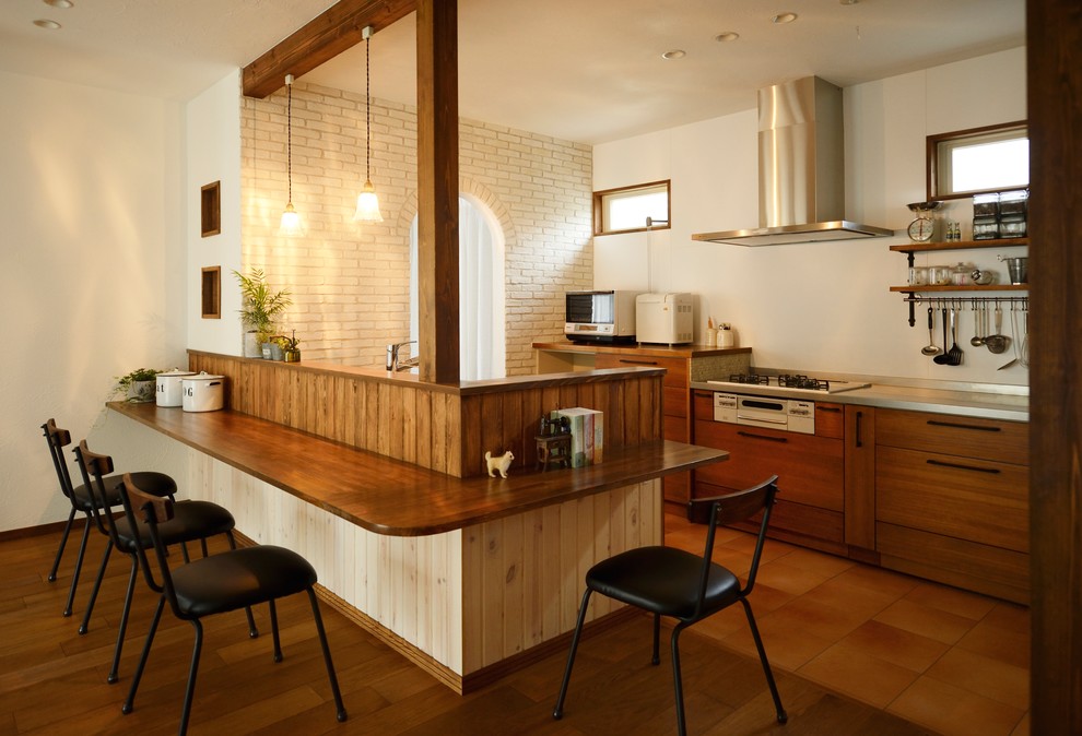 Пример оригинального дизайна: параллельная кухня-гостиная в восточном стиле с плоскими фасадами, фасадами цвета дерева среднего тона, столешницей из нержавеющей стали, белым фартуком, полуостровом и коричневым полом