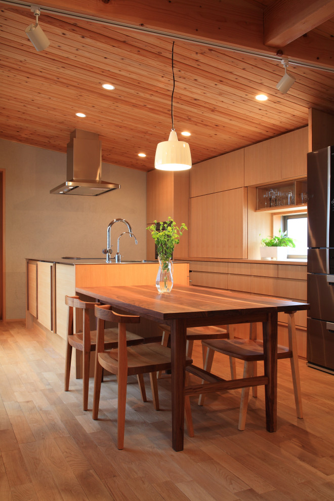 Foto på ett funkis brun kök, med mellanmörkt trägolv, släta luckor, skåp i mellenmörkt trä, träbänkskiva, en köksö och brunt golv