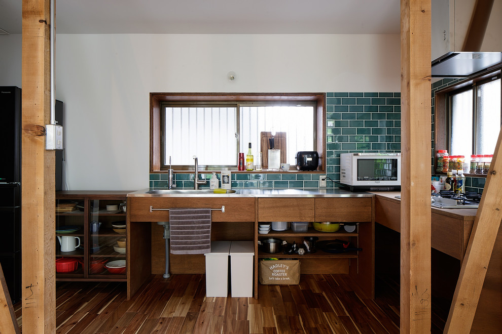 Photo of a world-inspired l-shaped kitchen in Yokohama with an integrated sink, flat-panel cabinets, stainless steel worktops, green splashback, metro tiled splashback, brown floors, grey worktops, dark wood cabinets and dark hardwood flooring.
