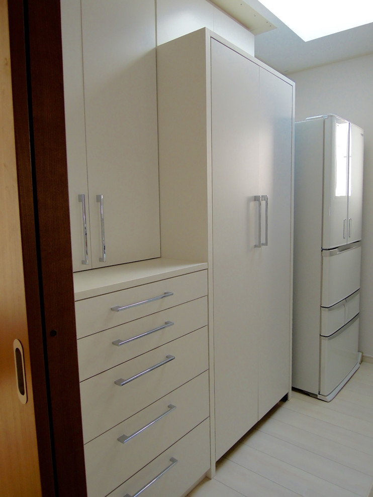 Modelo de armario y vestidor moderno con armarios con paneles lisos, puertas de armario blancas, suelo de contrachapado y suelo blanco