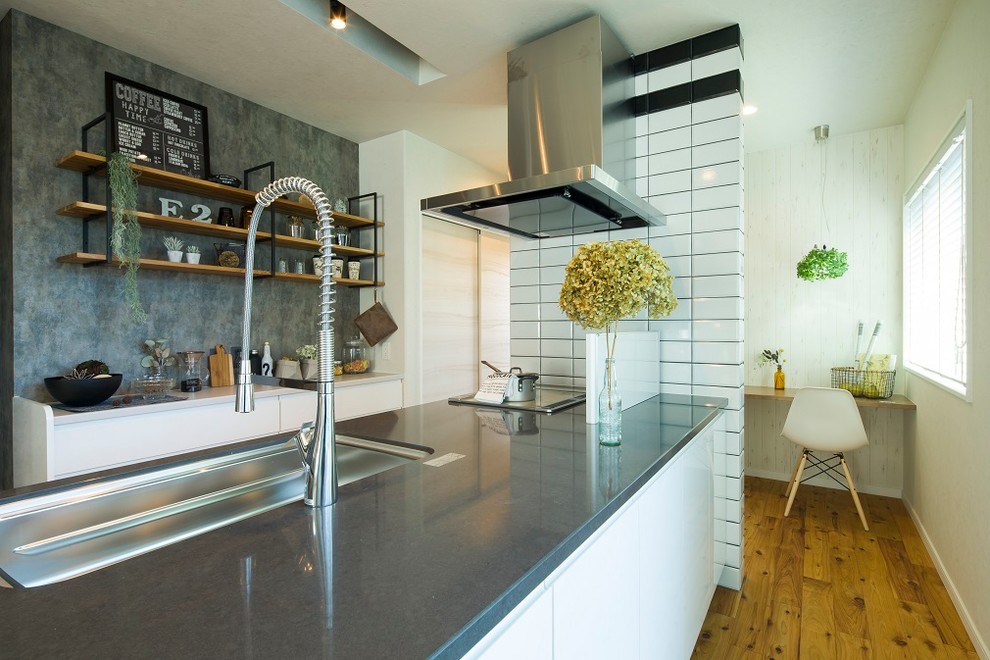 他の地域にあるインダストリアルスタイルのおしゃれなキッチン (シングルシンク、フラットパネル扉のキャビネット、白いキャビネット、無垢フローリング、茶色い床) の写真