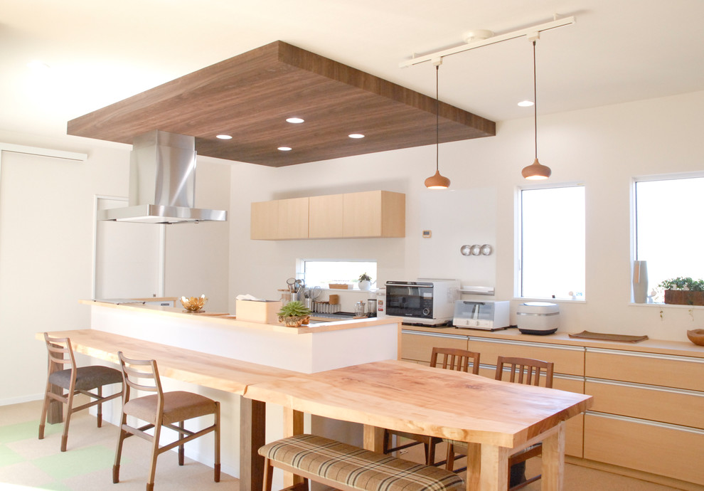 Inredning av ett asiatiskt stort linjärt kök och matrum, med en integrerad diskho, skåp i mellenmörkt trä, bänkskiva i koppar, en köksö och flerfärgat golv