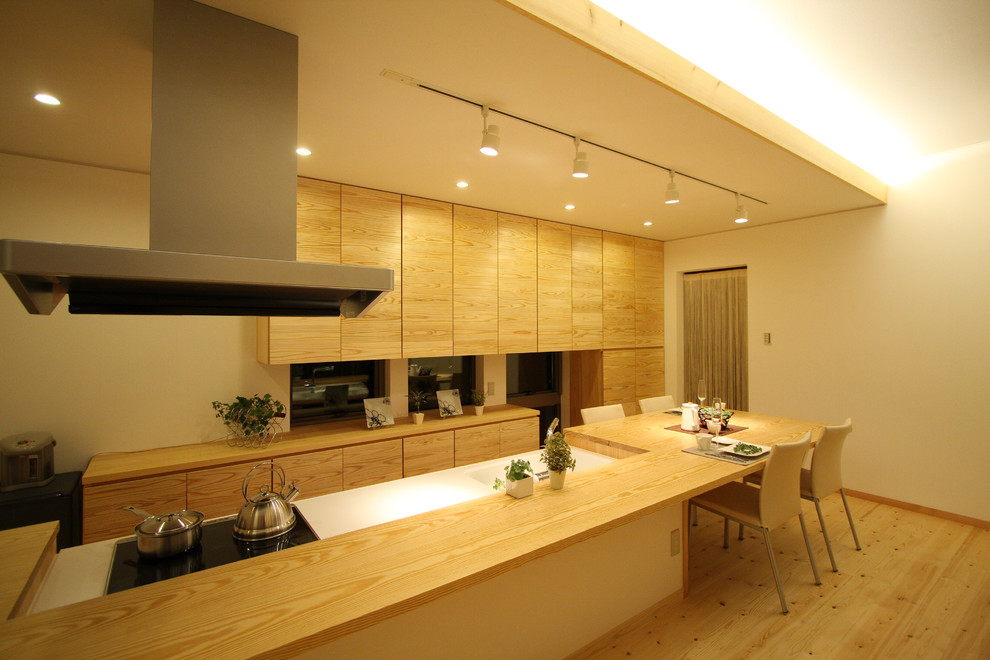 Cette image montre une cuisine ouverte asiatique en bois brun avec un évier intégré, un placard à porte plane, un sol en bois brun et un sol marron.