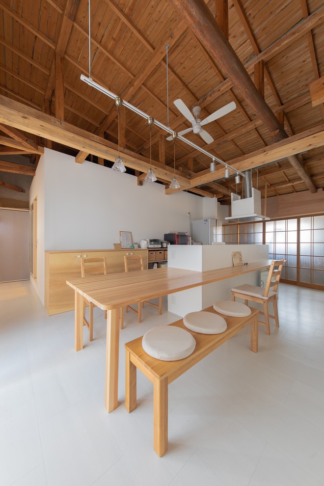 Идея дизайна: параллельная кухня в восточном стиле с обеденным столом, плоскими фасадами, светлыми деревянными фасадами, деревянной столешницей, белым фартуком, островом, белым полом и коричневой столешницей