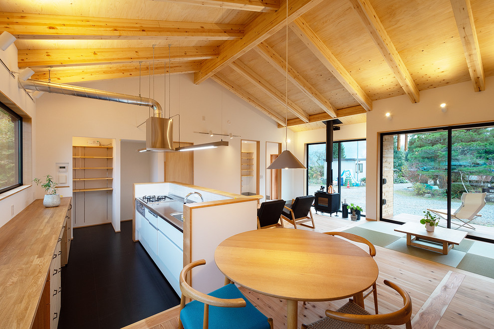 Idéer för ett stort minimalistiskt linjärt kök med öppen planlösning, med en integrerad diskho, släta luckor, vita skåp, bänkskiva i rostfritt stål, stänkskydd i mosaik, en köksö, vitt stänkskydd, rostfria vitvaror, vinylgolv och svart golv