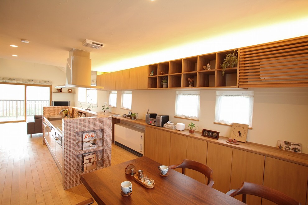 Cette photo montre une cuisine ouverte scandinave avec un placard à porte plane, une crédence multicolore, un sol en bois brun et îlot.