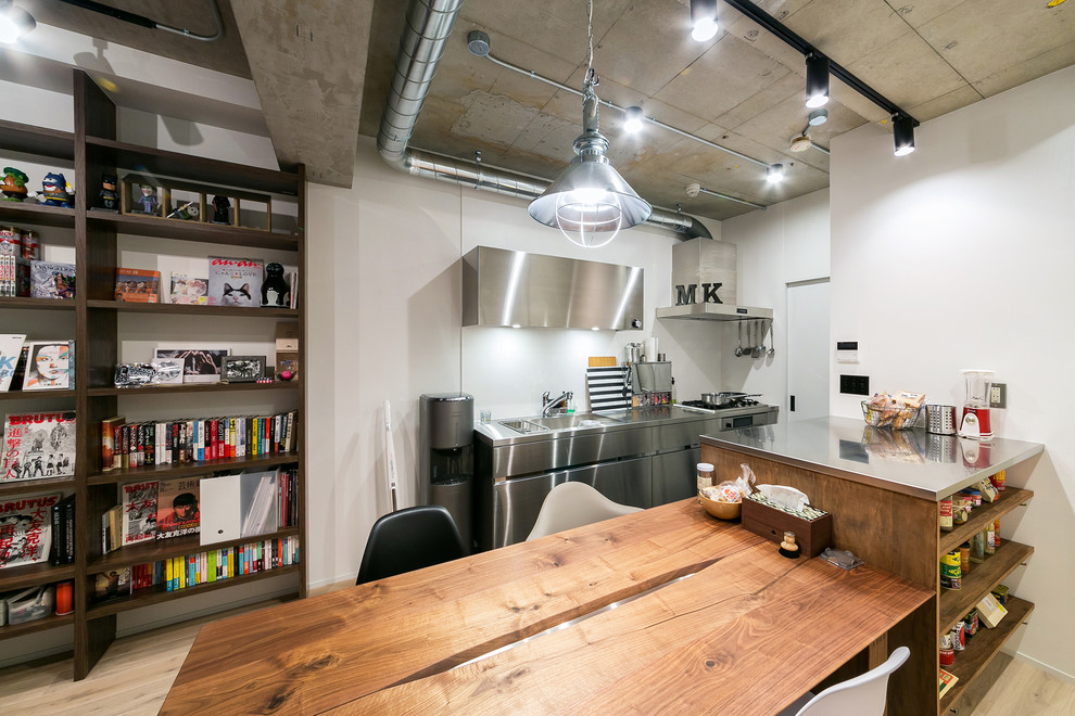 東京23区にある小さなインダストリアルスタイルのおしゃれなキッチン (フラットパネル扉のキャビネット、ステンレスキャビネット、ステンレスカウンター、白いキッチンパネル、シルバーの調理設備、淡色無垢フローリング) の写真
