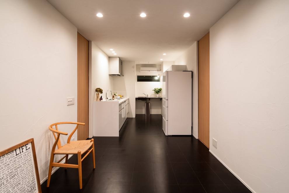 他の地域にあるコンテンポラリースタイルのおしゃれなキッチン (コルクフローリング、黒い床、シングルシンク、フラットパネル扉のキャビネット、白いキャビネット、白いキッチンパネル、白いキッチンカウンター) の写真