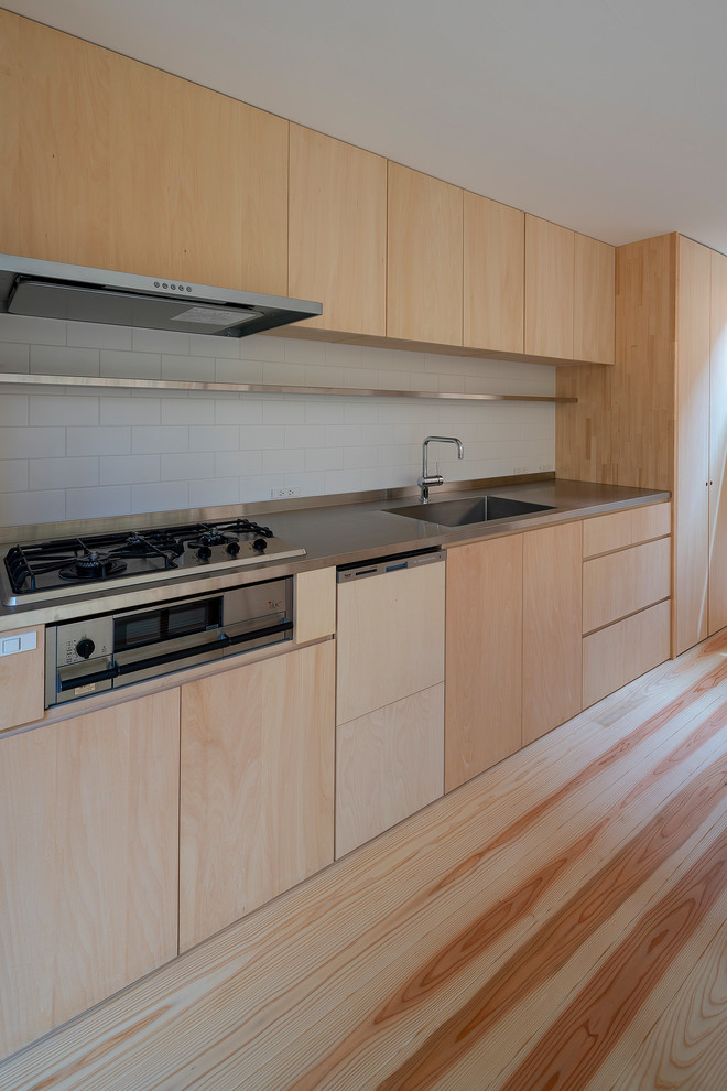 Example of a mid-sized single-wall painted wood floor and beige floor open concept kitchen design in Osaka with an integrated sink, flat-panel cabinets, light wood cabinets, stainless steel countertops, beige backsplash, wood backsplash, stainless steel appliances and an island